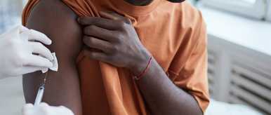 Close% Up%  Of%  Adult%  African American%  Man%  Looking%  Away%  While%  Getting%  Covid%  Vaccine%  In%  Clinic%  Or%  Hospita